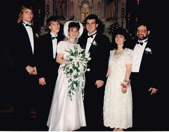 Friends and family gather in a church, celebrating a couple's wedding in formal attire and flowers.