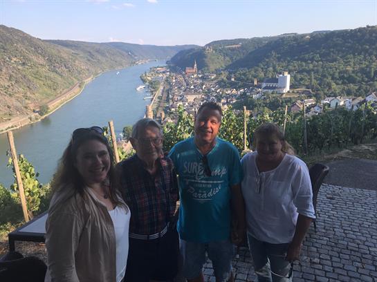 Four friends pose happily, capturing a memorable moment by the Rhine River surrounded by hills.