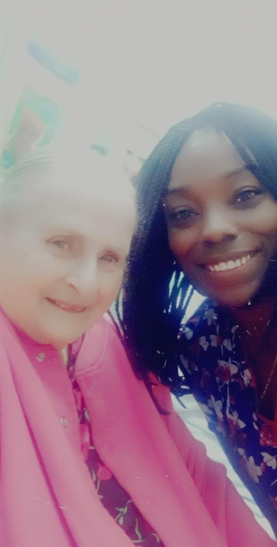 Two women enjoy each other's company outdoors, sharing smiles in a joyful moment of connection.