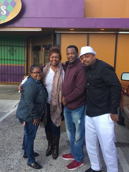 Four friends share smiles and laughter outside a vibrant location on a sunny day.