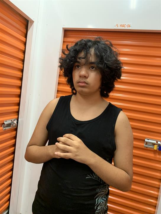A young person with curly hair appears contemplative in a brightly colored storage space.