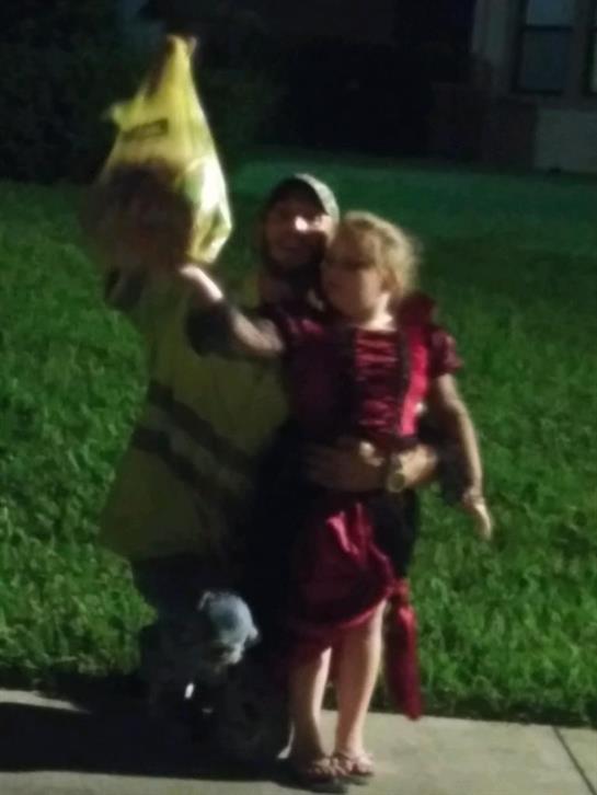 Two children dressed in colorful costumes are joyfully playing outdoors during evening hours.