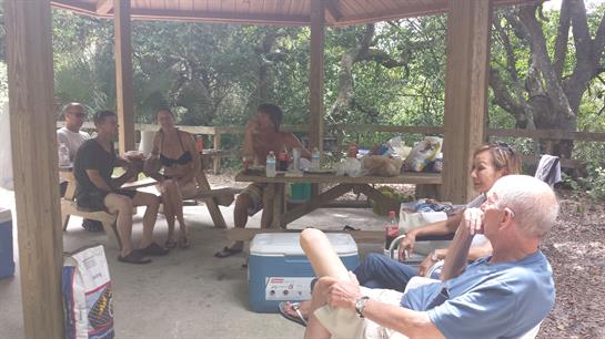 Friends socialize and unwind in a shaded area surrounded by trees during a warm afternoon.