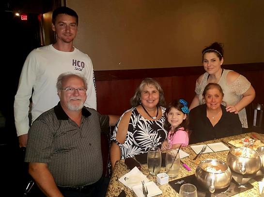 Family members share laughter and conversation around a table during dinner at a restaurant.