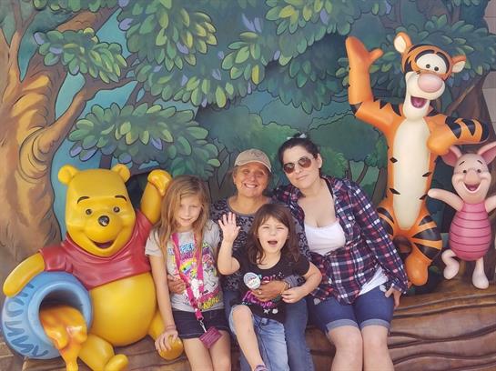 Family joyfully poses with animated characters, creating lasting memories at the theme park.