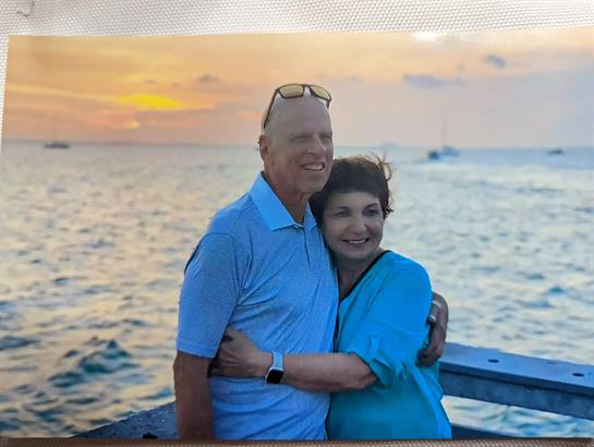 A happy couple on a pier enjoys the ocean view as the sun sets.
