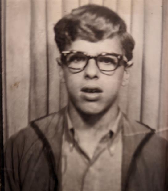 A young man in glasses and a casual jacket displays a typical 1960s neutral look.
