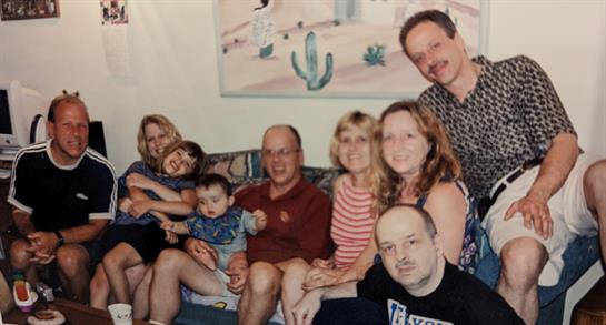 A cheerful family gathers in a living room sharing smiles and laughter while seated together.