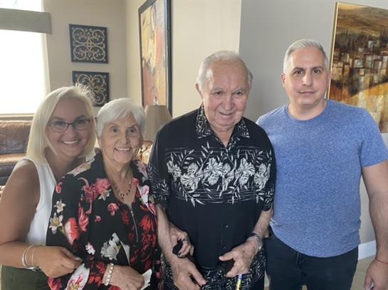 Four family members pose happily in a warm living room, enjoying each other's company and smiles.
