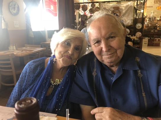 Two elderly individuals share a joyful meal together in a cozy restaurant, smiling warmly.