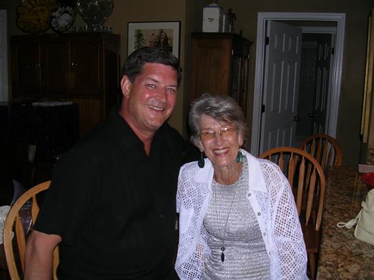 A man and a woman share a joyful moment at a home gathering, smiling together in a cozy setting.