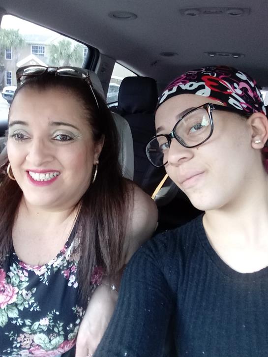Two women are seated in a vehicle, smiling and enjoying each other's company during the day.