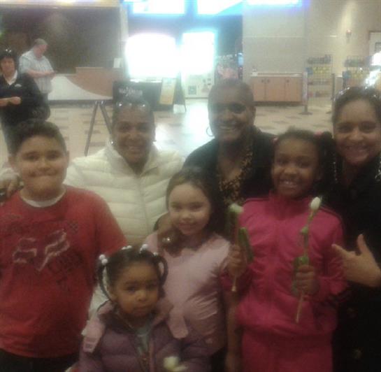 A joyful gathering of friends and children, smiling and holding flowers while celebrating.