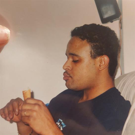 A man sits comfortably on a couch, absorbed in examining a small wooden item.