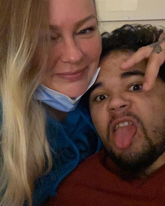 Two friends pose for a fun and lighthearted moment at home, showing their playful side.