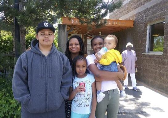 A family enjoys a sunny day in a park, smiling and posing together with ice cream treats.