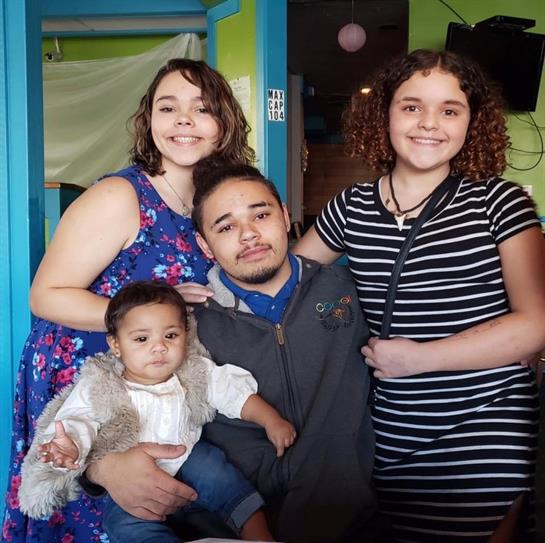 Family members smile together, celebrating a special moment in a vibrant setting.
