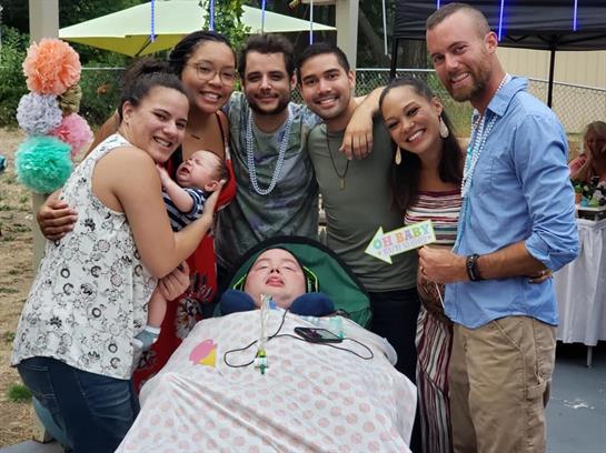 A group of friends and family members gathers joyfully outdoors, sharing smiles and warmth.