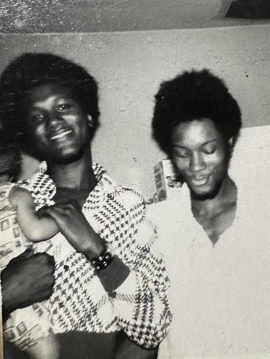 Two friends share a joyful moment indoors, laughing and celebrating together with a child.