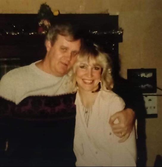 A happy couple stands close together, sharing a joyful moment in a decorated indoor space.
