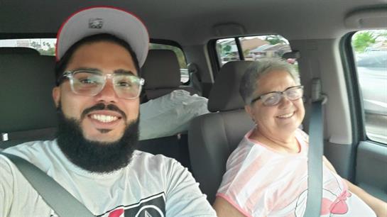 A man and a woman are smiling and taking a joyful selfie in a car, showing happiness.