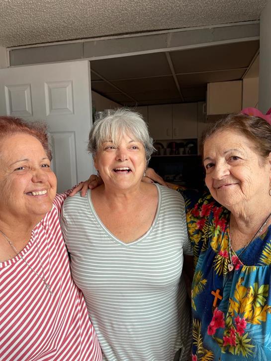 Three cheerful women are gathered in a warm living space, sharing joyful moments together.