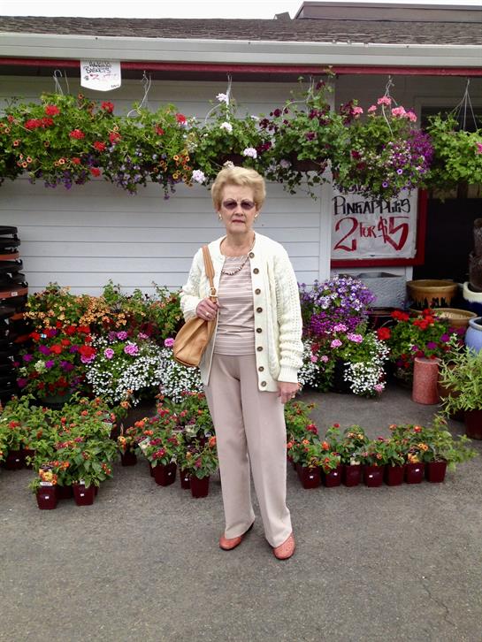 A woman enjoys a day out at a market, surrounded by vibrant flowers and plants.