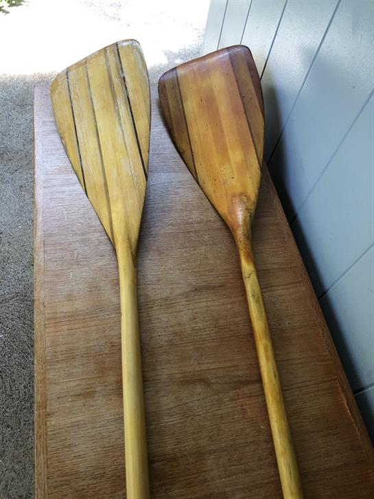 Two handcrafted wooden paddles rest on a table, highlighting their natural grain and design.