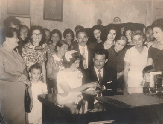 A joyful group gathered around a man and woman at a table for a special celebration.