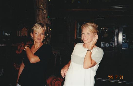 Two women are smiling and posing for the camera while enjoying a fun night at a bar.
