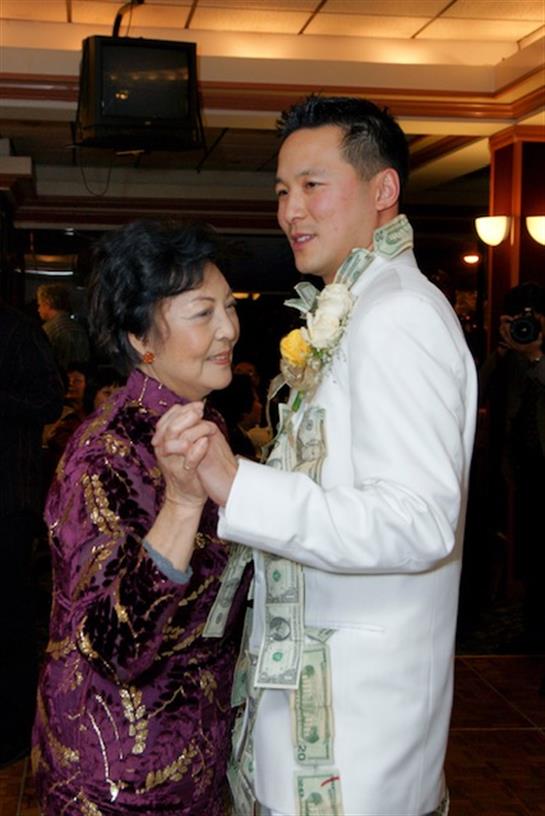 A young man dances closely with an older woman, celebrating a special event in a luxurious setting.