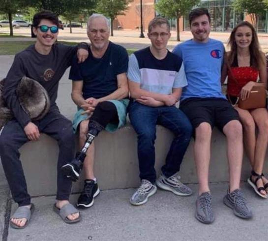 Group of friends casually sitting on a bench in a park on a sunny day, smiling and relaxed.