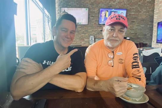 Two men sit at a table, sharing a meal and engaging in conversation at a laid-back restaurant.