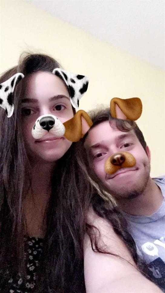 A couple poses closely together with fun dog filters on their faces, creating a playful atmosphere.