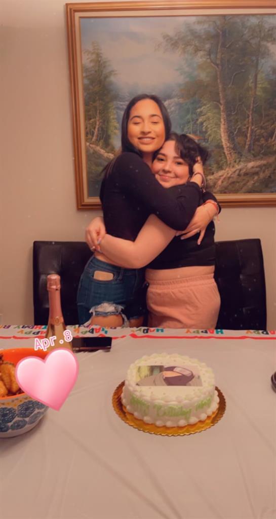 Two friends embrace joyfully at a table adorned with festive decorations and treats.