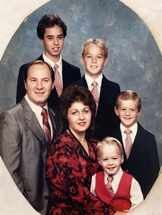 Six family members pose for a formal portrait in their coordinated outfits and ties.