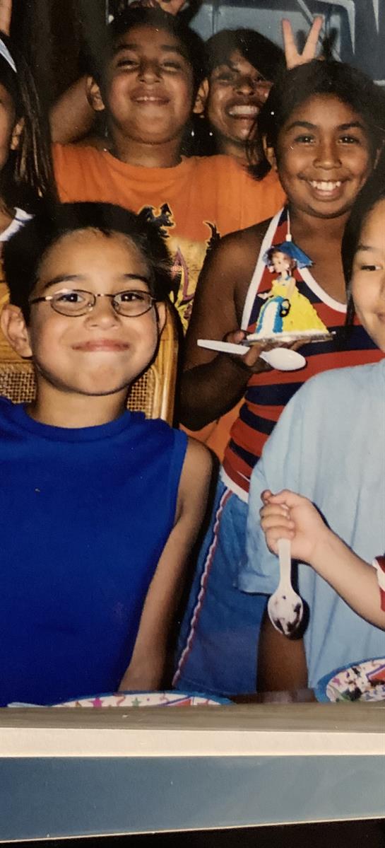 Two joyful kids are smiling while holding spoons at a vibrant birthday celebration.