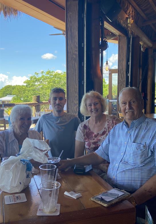 A group of four seated at a table, sharing smiles and conversation during a sunny afternoon.