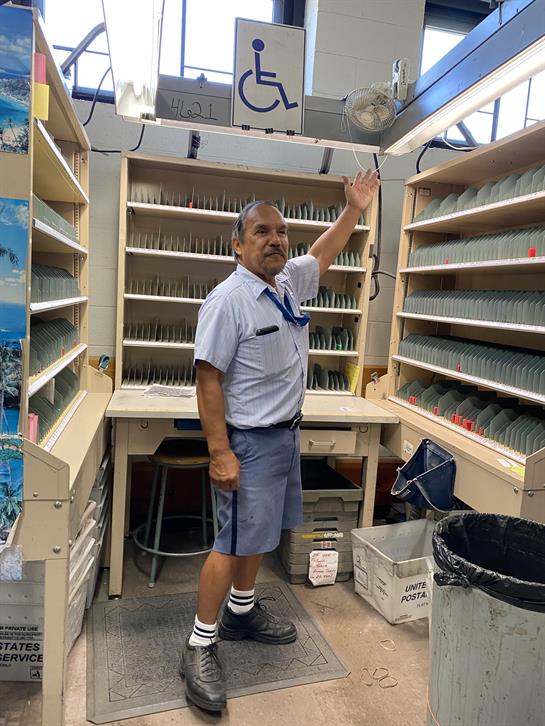 A man in a uniform is demonstrating a library area with numerous book-filled shelves.