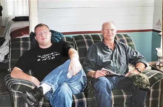 Two men relax on a couch in a comfortable living room, enjoying each other's company.
