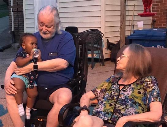 An elderly couple enjoys each other's company on a porch with a young child.