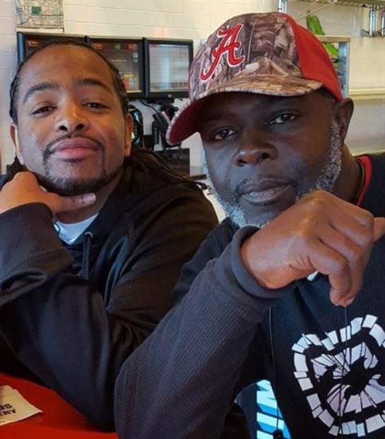 Two friends sit close together at a table, smiling and enjoying a meal in a cozy restaurant.