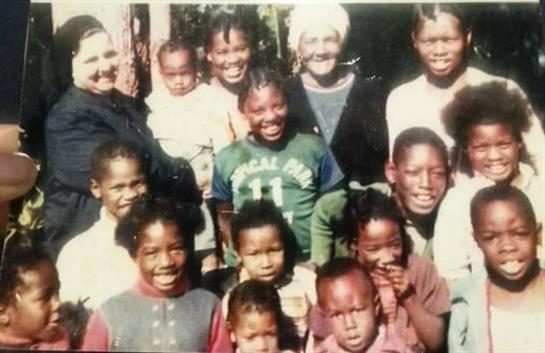 A joyful family reunion showcases children and adults smiling together in a sunny outdoor setting.