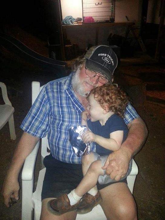 A joyful grandfather holds his giggling grandson while enjoying a relaxed summer night together.