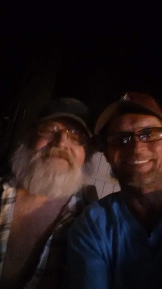 Two men share a joyful night outdoors, smiling and enjoying each other's company.