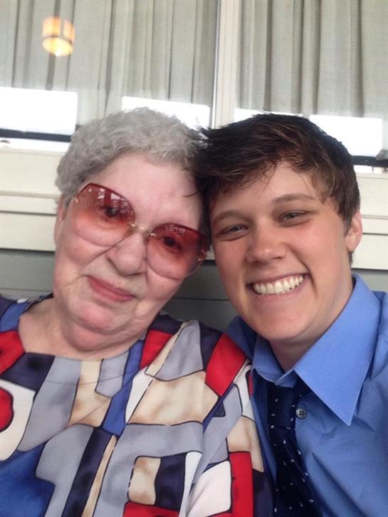 A young person smiles next to an older woman, both enjoying a cheerful day together.