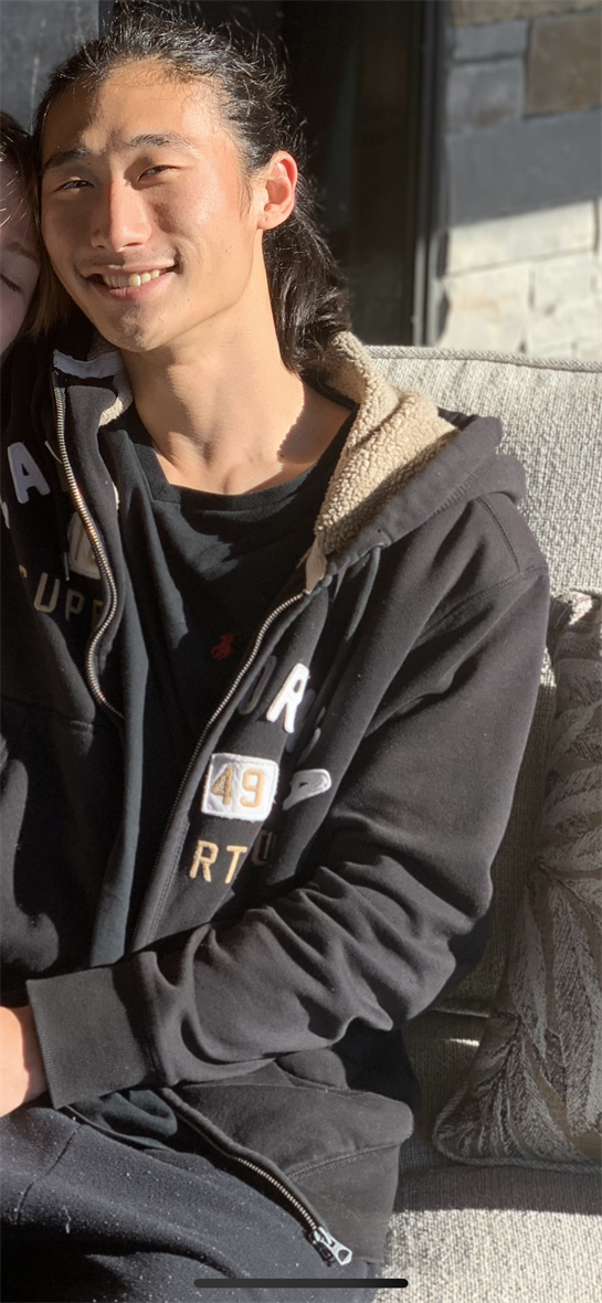 Individual sits comfortably in a well-lit indoor setting, wearing a soft hoodie.