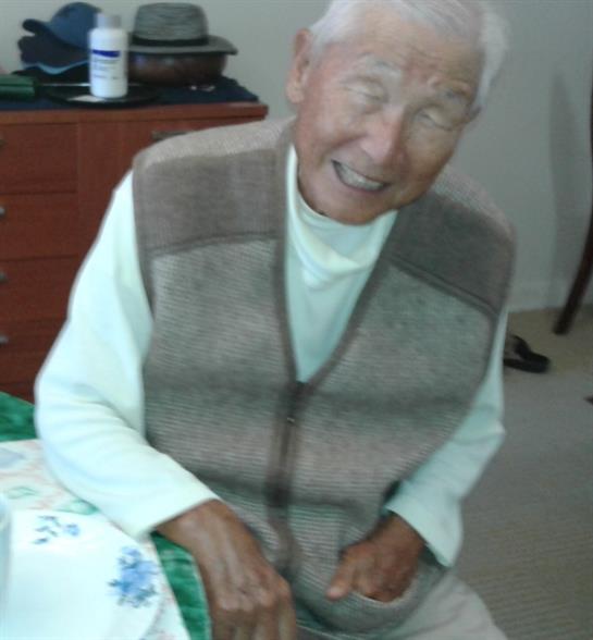 An elderly man shares a joyful smile in his comfortable living space, radiating happiness.