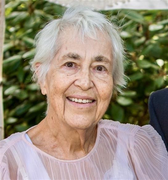 An elderly woman with silver hair enjoys a cheerful moment at a garden party with friends.