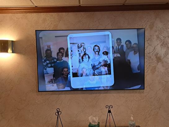 A large screen displays a joyful family gathering in a cozy room, full of smiles.